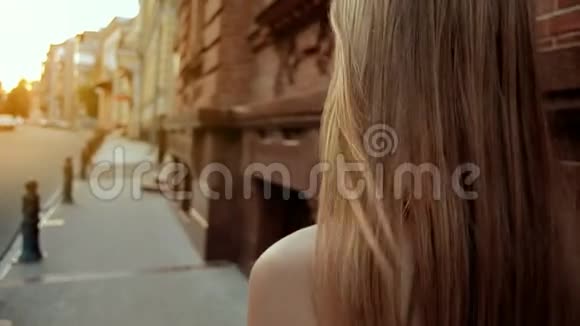 金发的年轻女孩沿着街道走视频的预览图