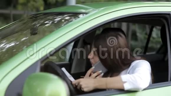 坐在车里的女孩在电话里谈生意在笔记本上做笔记视频的预览图