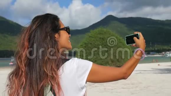 混合种族年轻的亚洲白人妇女自画像照片与移动手机智能手机在马里布海滩高清视频的预览图