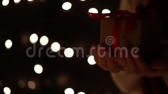 女性步行者手持圣诞礼品盒背景上有圣诞树视频的预览图