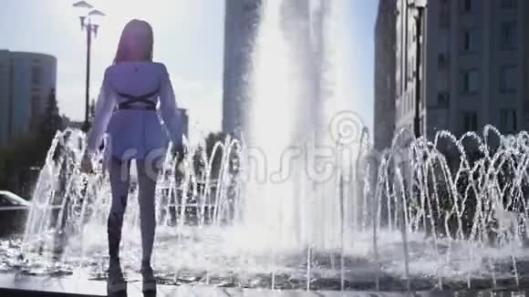 一个美丽的女孩站在喷泉的边缘快乐地旋转着高清1920x1080慢动作视频的预览图