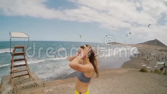 风天年轻迷人的女人站在海边在后台放风筝的地方视频的预览图