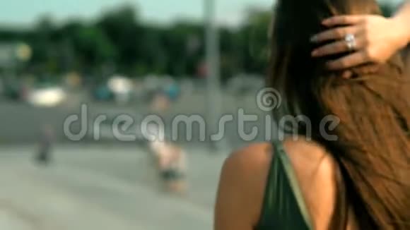 阳光明媚的一天年轻的黑发女人在街上散步视频的预览图