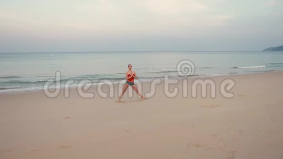 日出前在海滩上穿红色运动服的女人练习瑜伽健身运动视频的预览图