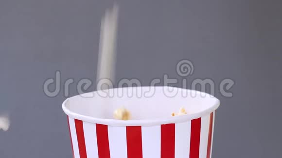爆米花落在灰色背景上的条纹红白桶里视频的预览图