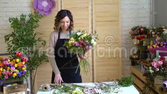 工作中的花商年轻漂亮的金发女人手里拿着时尚的现代花束里面有佩恩和玫瑰视频的预览图