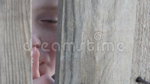惊恐的少年男孩透过栅栏或门口的缝隙窥视露出一根手指表示沉默视频的预览图