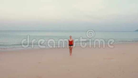 日出前在海滩上穿红色运动服的女人练习瑜伽健身运动视频的预览图