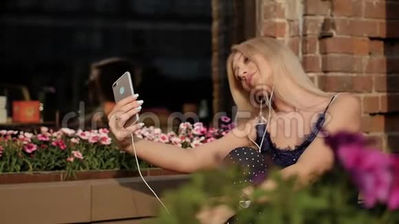 穿着西装的年轻女商人在智能手机上听音乐自拍美丽的金发女郎正躺在视频的预览图