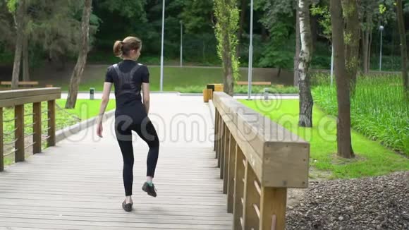 健身妇女在木桥训练前伸展双腿慢动作视频的预览图