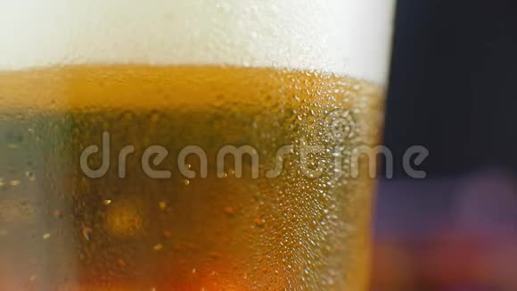 特写慢镜头冷啤在一个杯子里大滴和气泡在啤酒里视频的预览图