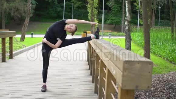 年轻女子在公园的木桥上伸展训练慢动作视频的预览图