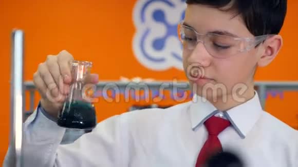 男生在学校化学课上看试管做实验视频的预览图