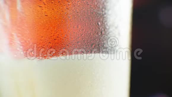 啤酒正倒入角玻璃中IPA启动了在装有水滴的杯子里喝冷光啤酒啤酒制造波浪视频的预览图