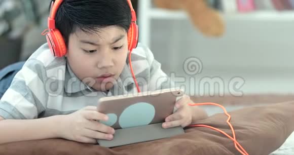 近距离拍摄的亚洲青少年躺在地板上玩平板电脑视频的预览图