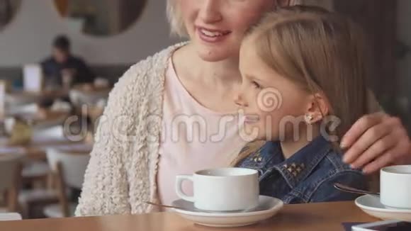 女人在咖啡馆给女儿看东西视频的预览图