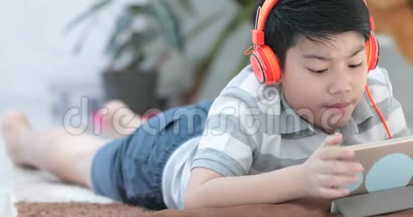 近距离拍摄的亚洲青少年躺在地板上玩平板电脑视频的预览图