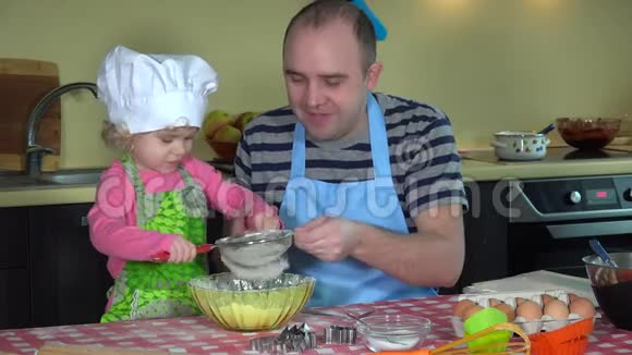 快乐的男人带着他可爱的女儿女孩筛面粉做蛋糕视频的预览图