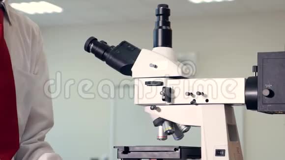 在学校实验室里通过显微镜看生物学的小男孩视频的预览图