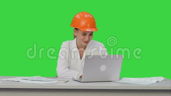 女建筑专家在硬帽有在线视频聊天与朋友在绿色屏幕铬键视频的预览图