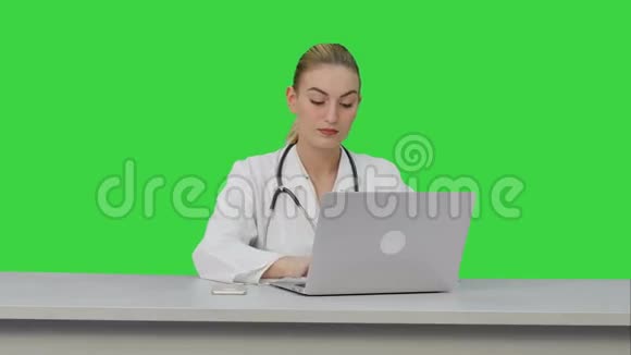 女医生在绿色屏幕上的笔记本电脑上工作Chroma键视频的预览图