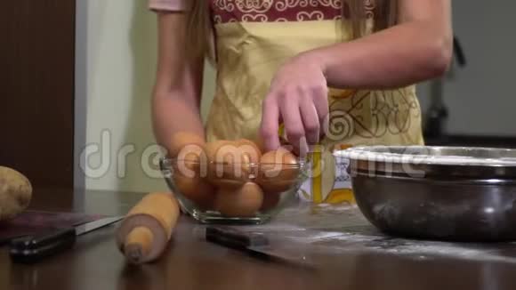 当女人用叉子搅拌时女人的手拿着一个鸡蛋打破刀子把它倒进一碗面粉里视频的预览图