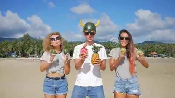 愚蠢的素食者在海滩上有乐趣并与异国情调的泰国水果跳舞泰国范甘高清慢速运动视频的预览图
