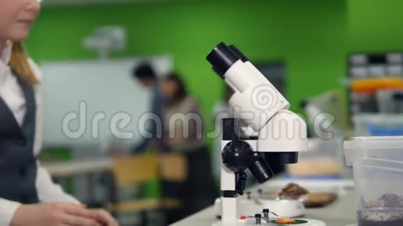 学校研究实验室里的年轻学生在显微镜下观察视频的预览图