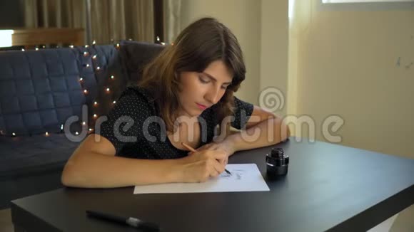 一位年轻女子用刻字技巧在纸上书写书法的特写镜头她写着梦想视频的预览图