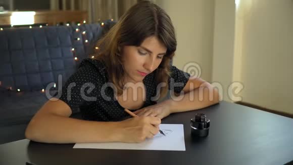一位年轻女子用刻字技巧在纸上书写书法的特写镜头她写着梦想视频的预览图