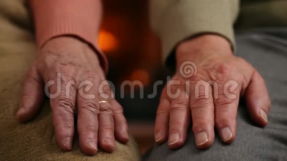 壁炉前男人和女人的双手在年老时互相安慰视频的预览图
