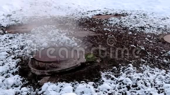 冬季公园雪中的卫生下水道盖产生了近距离蒸汽融化的雪视频的预览图