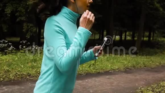 公园里戴着耳机的快乐运动女人视频的预览图