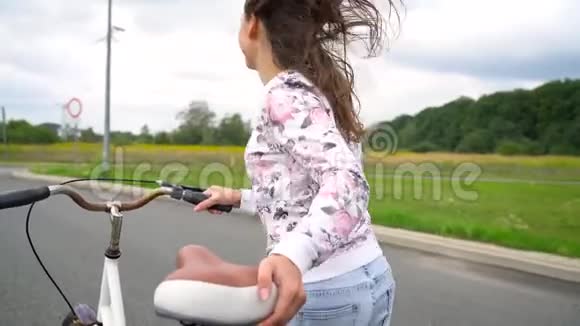 女人笑着骑着自行车沿着街跑慢动作视频的预览图
