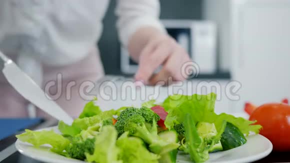 厨房提供新鲜的有机绿色沙拉手拿刀叉将生菜与西兰花和黄瓜混合视频的预览图