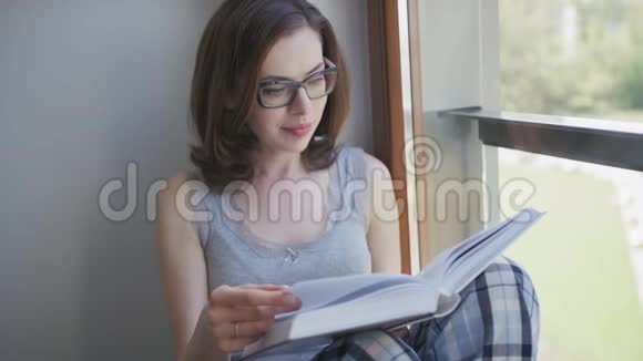 漂亮的女人坐在窗边看书视频的预览图