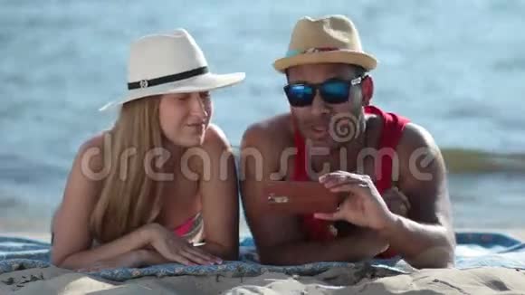 在海滩上用手机自拍的快乐情侣视频的预览图