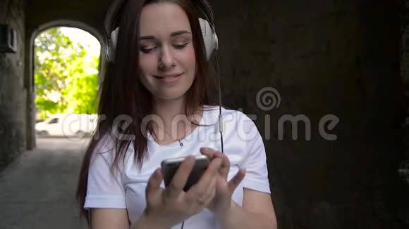 A女孩耳机散步穿过城市听听音乐从电话视频的预览图