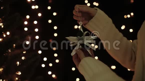 女人在圣诞树上装饰着星星花环在薄光的背景上视频的预览图