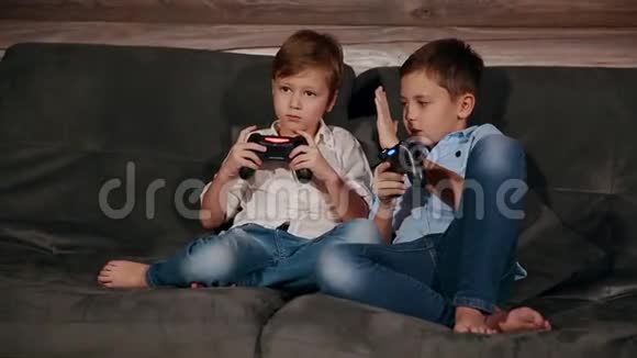 两个兄弟坐在沙发上非常情绪化地用无线操纵杆玩电子游戏视频的预览图