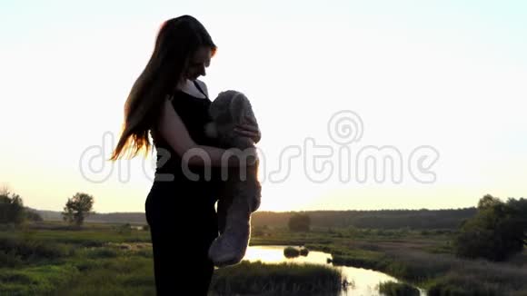 怀孕的女孩在4K日落时和熊玩视频的预览图