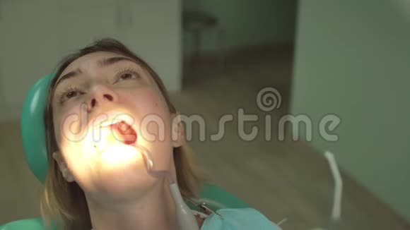 带牙科诊所和特殊照明的美丽妇女在牙科椅上的特写视频的预览图