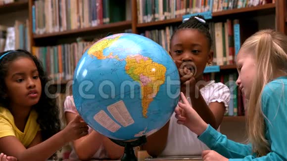 可爱的小女孩在图书馆里看地球仪视频的预览图