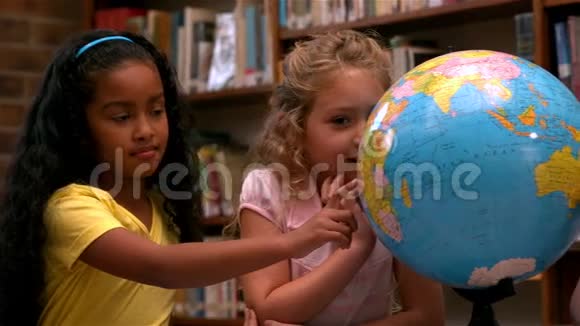 可爱的小女孩在图书馆里看地球仪视频的预览图