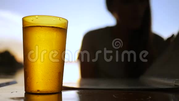 酒吧的桌子上摆着一杯冰镇饮料在日落时分女孩从菜单上选择食物视频的预览图