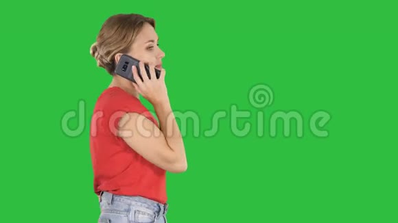 金发女人在绿色屏幕上走来走去在电话里说话Chroma键视频的预览图