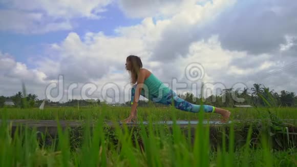 一个年轻女子在美丽的稻田里练习瑜伽的慢动作稳定镜头视频的预览图