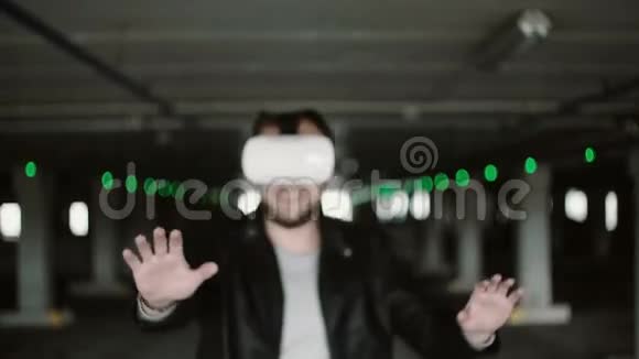 年轻人在停车场使用虚拟现实眼镜男乘VR耳机走过过道4K视频的预览图
