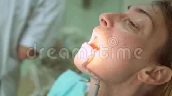 为美丽的幸福女性患者提供牙科检查和特殊照明视频的预览图
