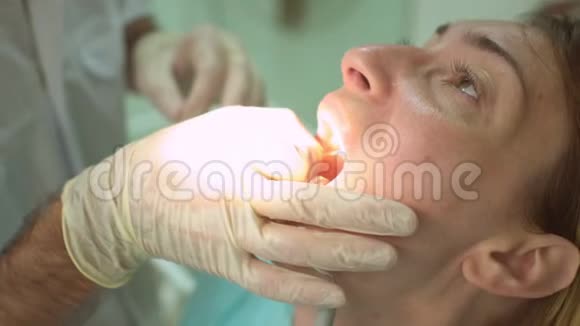 在牙科椅上用牙科检查和特殊照明为美丽的幸福女性患者做特写视频的预览图